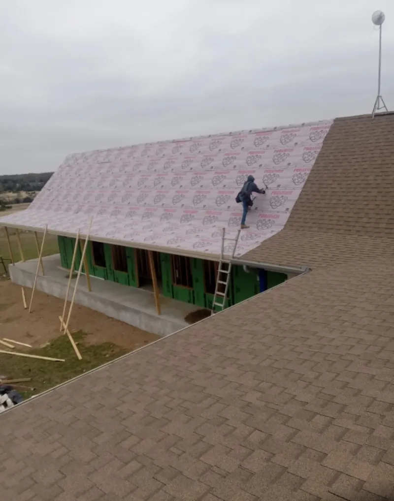 Worker preparing underlayment for a metal roof installation in Schenectady